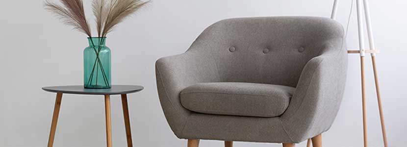 Modern grey armchair next to a small side table with a green vase