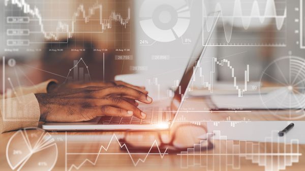 Unrecognizable African American employee using laptop in office, collage with financial info on transparent screen Unrecognizable African American employee using laptop, collage data info on transparent screen.